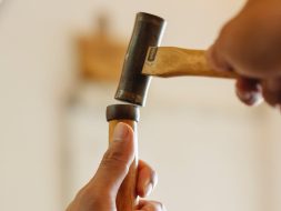 Low angle of crop anonymous craftsman hammering instrument while working in joinery workshop