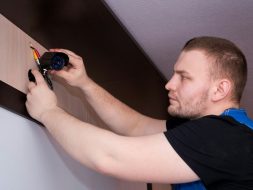 a man working on a wall with a screwdriver