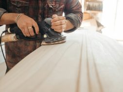 man using sander on beige wooden surface