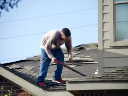 a man with a hammer on top of a roof