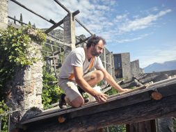 Focused man building roof of wooden construction